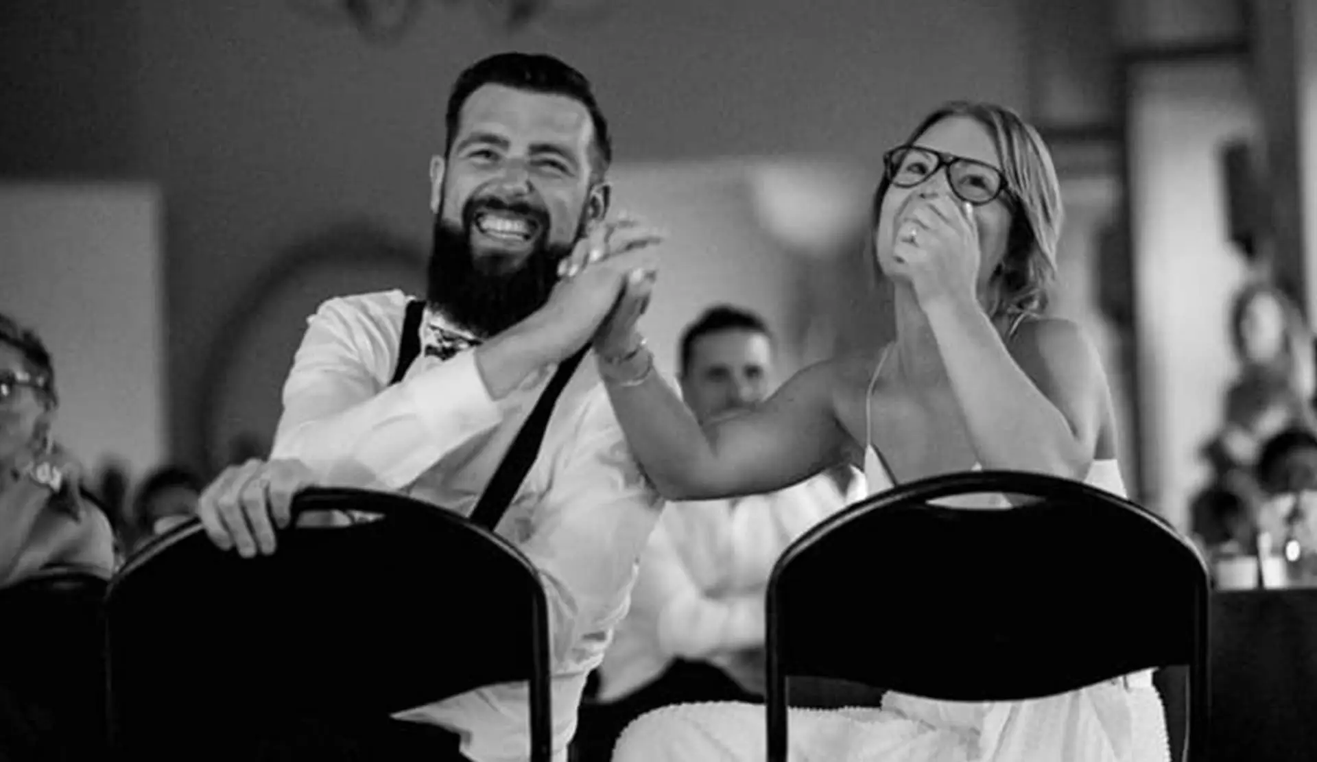 Mariés complices et souriants pendant la soirée, en noir et blanc